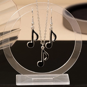 Silver music note necklace and earrings set with black enamel finish on clear display