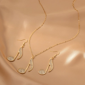 Golden music note jewelry set with crystal necklace and earrings on silk satin fabric