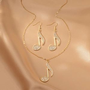 Detail of gold musical note jewelry set with pave crystals on silk fabric