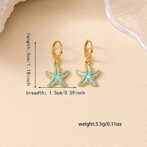 Blue enamel starfish drop earrings with gold hoops on a marine themed background