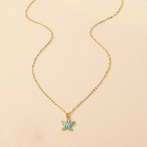 Détail d'un collier en chaîne dorée avec pendentif étoile de mer bleue émaillée