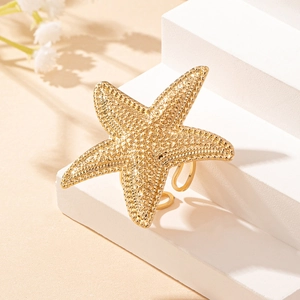 Macro view of golden starfish ring with beaded texture on white display block