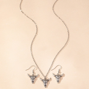 Detail of vintage bull skull jewelry set with engraved eye totem and antique silver finish