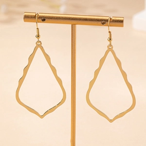 Élégantes boucles d'oreilles gouttes dorées avec bords ondulés sur un présentoir