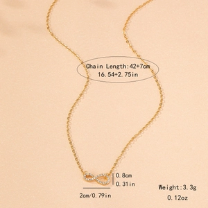 Elegant gold infinity symbol necklace with white crystals on a warm sand background