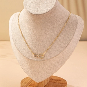 Elegant infinity necklace in gold with micro-inlaid diamonds on beige display