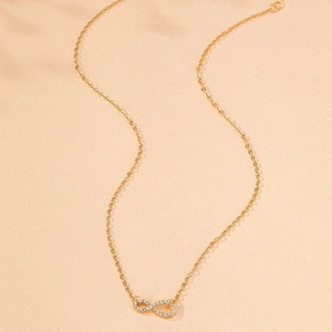 Close-up of golden infinity pendant necklace with sparkling white zircons on O-chain