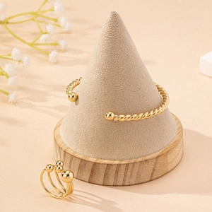 Elegant gold braided twist open bangle and beaded ring jewelry set on a suede stand