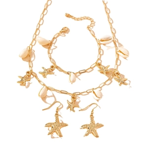 Goldenes Ozean Schmuckset mit Seestern-Anhängern und weißen Muscheln auf weißem Grund