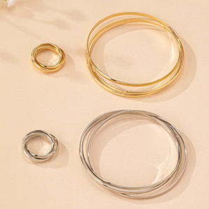 Detail of high-polish triple interlocking bangle and ring set in gold and silver finish