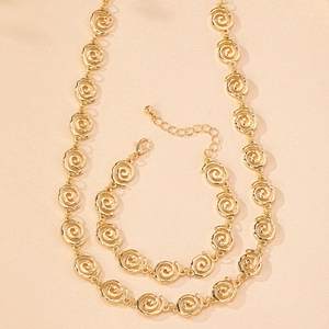 Polished gold jewelry set featuring spiral swirl necklace and bracelet with lobster clasp