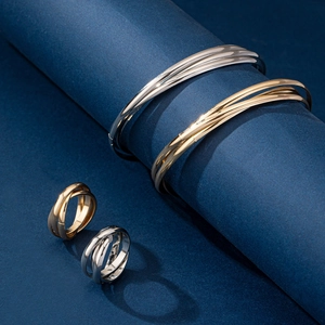 Detailed view of intertwined trinity rings and bracelets in gold and silver finishes