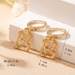 Detailed view of gold letter B earring with bamboo texture on a white marble stand