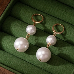 Boucles d'oreilles élégantes à double perle dorée sur une boîte à bijoux en velours vert