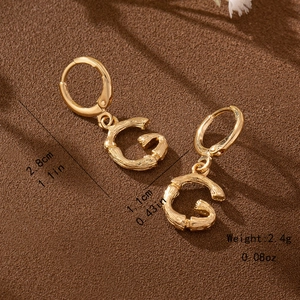 Detail view of bamboo texture gold letter G hoop earrings with dimensions 2.8cm and 2.4g weight