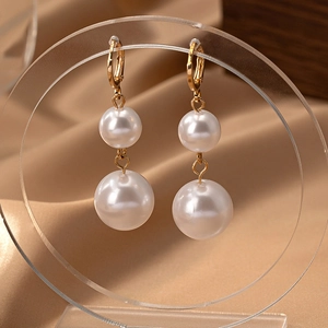 Élégantes boucles d'oreilles double perle dorée sur fond en soie luxueux