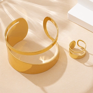 Detail of gold minimalist irregular hollowed-out cuff bracelet and matching ring set