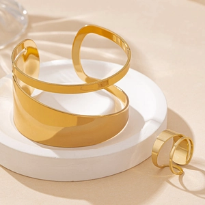 Elegant gold-tone geometric hollowed-out bracelet and ring jewelry set on stone stand