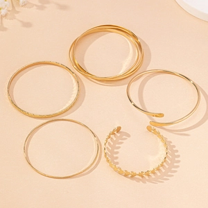 Detail of five-piece gold bangle set with minimalist geometric and leaf designs