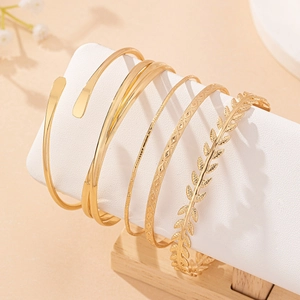 Elegant 6-piece golden bangle set with leaf motifs and geometric patterns on white stand