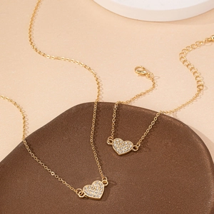 Elegant gold heart jewelry set with necklace and bracelet featuring sparkling rhinestones
