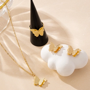 Parure bijoux papillon dorée avec collier, boucles d'oreilles et bague sur support blanc