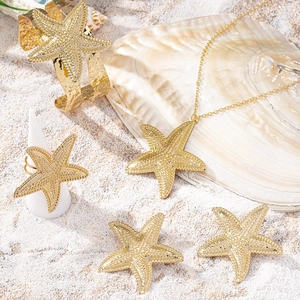 Parure de bijoux étoile de mer dorée avec collier, bracelet, bague et boucles sur sable
