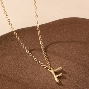 Minimalist gold necklace featuring letter F pendant with organic bamboo branch texture