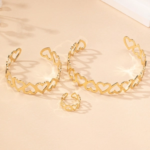 Detailed view of hollow heart jewelry set with bracelets and ring on textured background