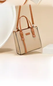 Detail of beige and brown leather handbag featuring contrast trim and golden hardware