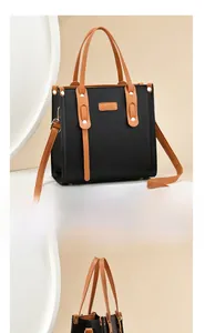 Detailed front view of black and brown contrast tote bag with tassel and brand logo