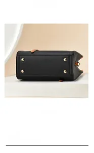 Detail view of the black textured leather bag base with four golden metal protective feet