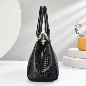 Side view of black faux leather handbag with lizard pattern and gold hardware details