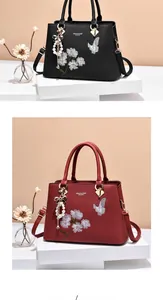 Détail de broderie florale et pendentif perle sur sacs à main noir et bordeaux