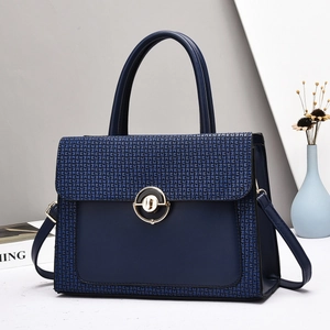 Navy blue textured leather tote bag with gold circular clasp and shoulder strap