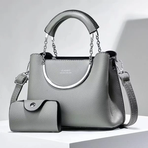 Détail du sac seau en cuir gris avec chaîne argentée et accessoires métalliques