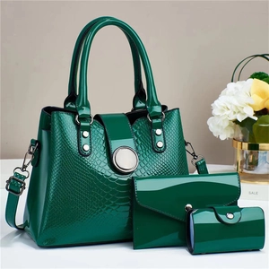 Detail of dark green embossed patent leather handbag set with silver hardware