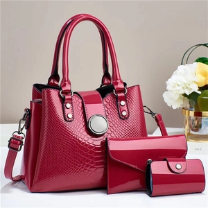Detail view of the glossy red faux leather textures and metal hardware of the 3-piece bag set