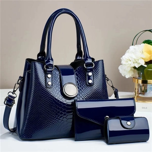 Close-up of deep blue crocodile texture lacquer leather handbag 3-piece set on a white table