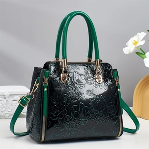 Three-piece tote bag set with floral embossing and vibrant green handles on black faux leather