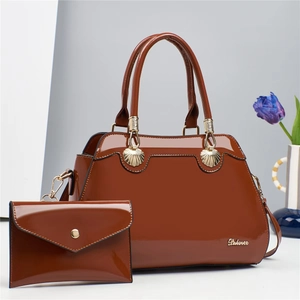 Detail of brown patent leather handbag set with gold shell clasp and matching clutch bag