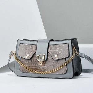 Détail d'un sac gris à motif lézard avec un fermoir rotatif doré en forme de G chic