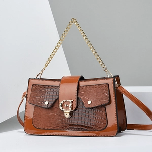 Détail de la texture lézard et du logo G doré sur le sac à bandoulière marron chic