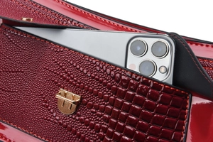 Détail d'un sac à bandoulière bordeaux motif lézard montrant la poche avant pour smartphone