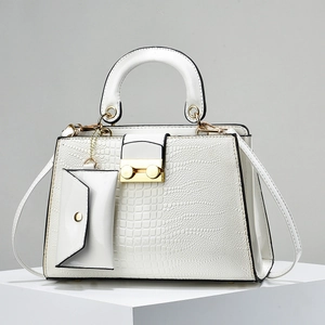 Detail of white crocodile textured handbag with golden buckle and mini purse attachment