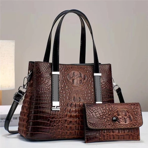 Detail der braunen Handtasche mit Krokodilmuster und passender Brieftasche mit Silberbeschlägen