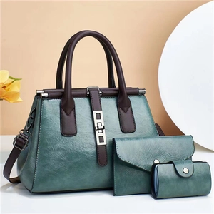 Close-up of three-piece vintage green handbag set with textured leather and silver clasp