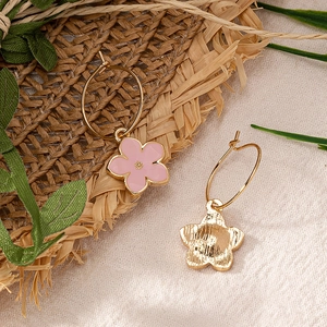 Élégantes boucles d'oreilles créoles dorées avec fleurs en émail rose sur fond rustique