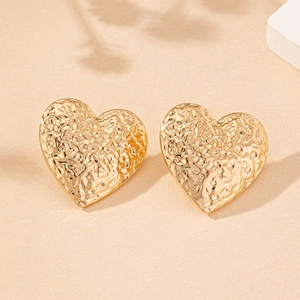 Detailed view of golden heart stud earrings with elegant hammered textured finish