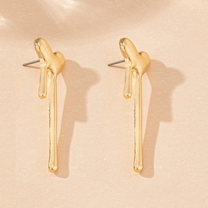 Macro shot of minimalist gold vertical melting heart earrings on beige textured card